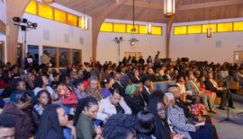 Crowded church interior with attendees seated.